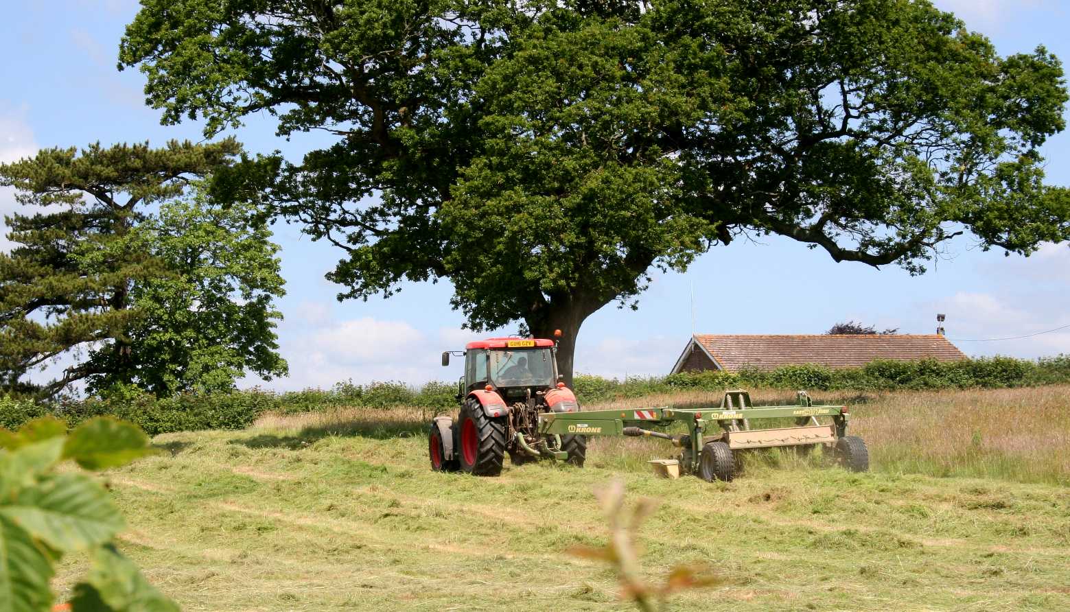 A tractor mowing the field adjacent to Herstmonceux museum in Sussex